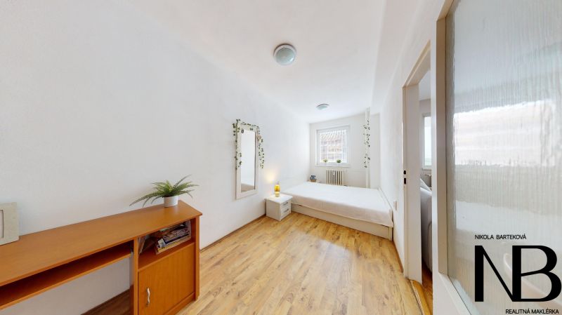 A bright bedroom in a 2-room apartment, with a bed and wooden flooring on K výstavisku street.