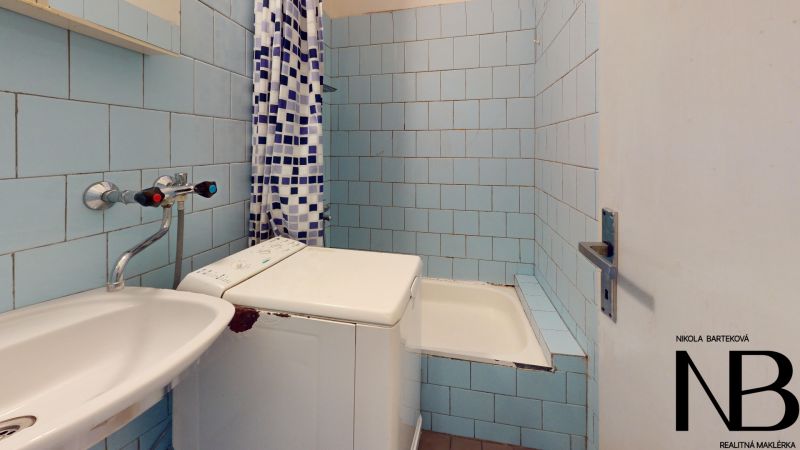 A bathroom in a 2-room apartment with blue tiles and a shower corner.