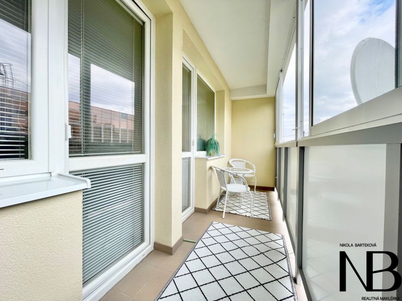 A glazed balcony of a 2-room apartment on K výstavisku street with comfortable armchairs and carpets.