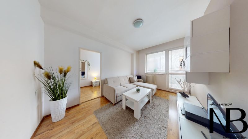 Living room in a two-room apartment on K výstavisku street with a comfortable sofa and wooden floor.