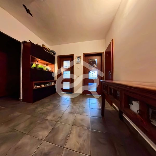 A hallway in a 4-room apartment with a shelf and tiled floor.