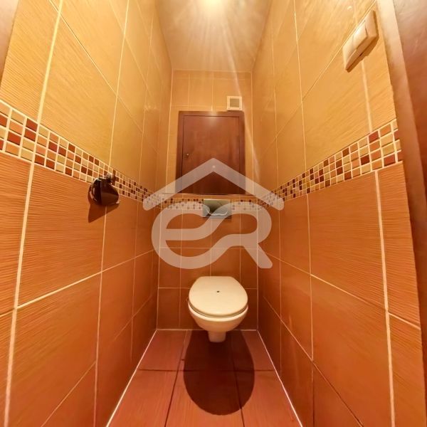 A toilet with brown tiles in a 4-room apartment.