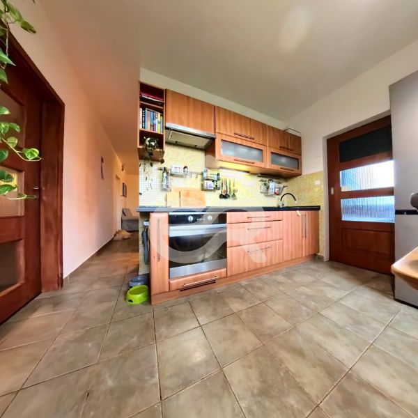 A kitchen in a 4-room apartment with tiles and a wooden decor kitchen unit.