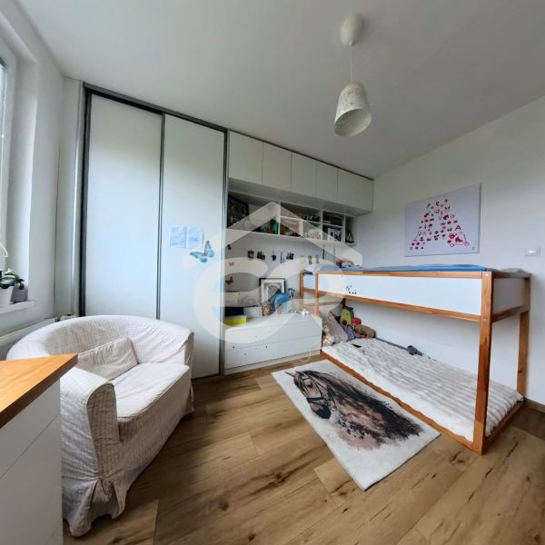 Children's room with a built-in wardrobe, bed, and floor with wooden decor in a 4-room apartment.