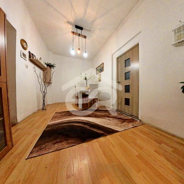 Interior of a family house with a wooden decor floor, a table, and decorative lighting.