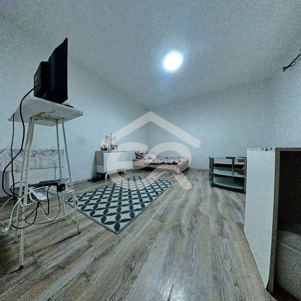 A room in a family house with a wooden decor floor and basic furniture.