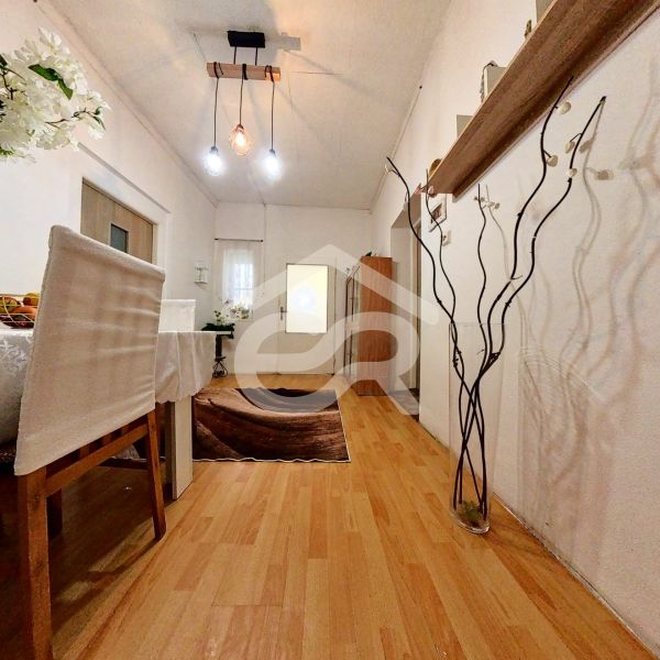 Interior of a family house with a dining table, wood-patterned flooring, and pendant lamps.