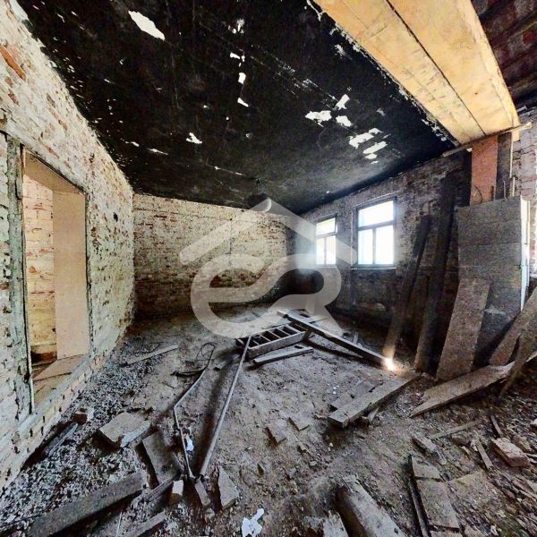 Unfinished interior of a family house with brick walls and a broken floor.