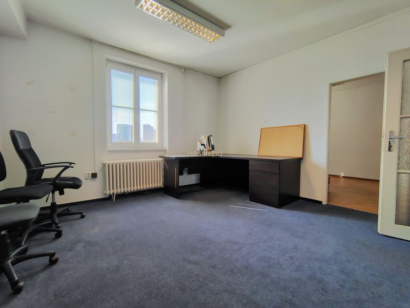 Offices with blue carpet, simply furnished, with a desk and chairs.