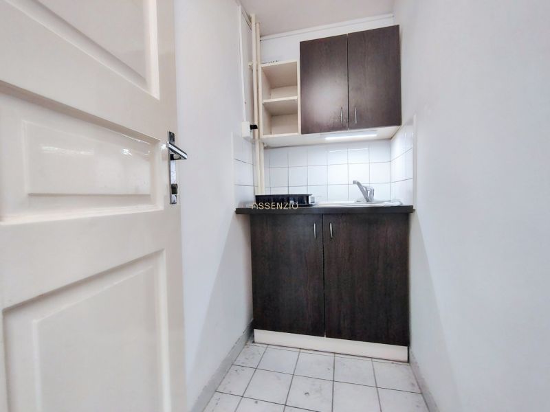 A compact kitchenette in offices with dark wood decor and white tiles.