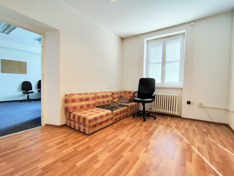 Offices with wood-patterned flooring, a sofa, a window, and a swivel chair.