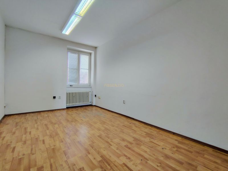An empty office with a wooden floor and a radiator under the window.