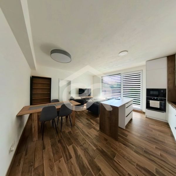 A spacious kitchen with built-in appliances and a wooden decor floor in a 3-room apartment.