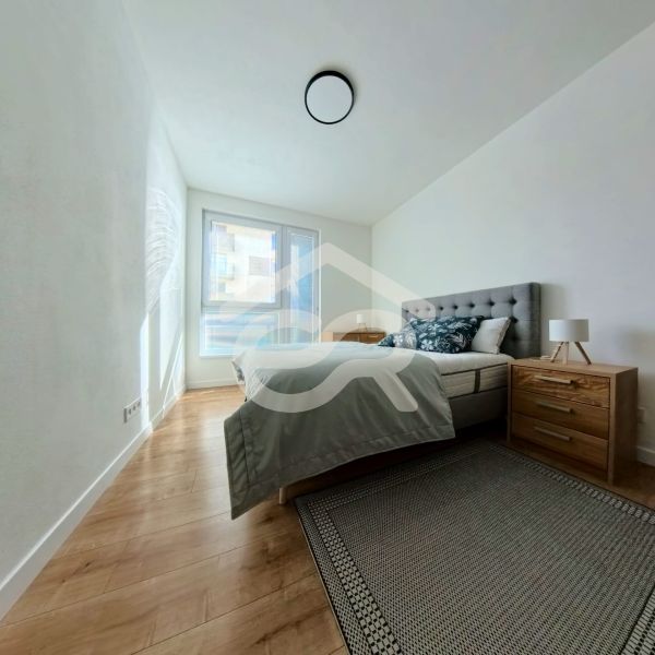 A bedroom in a 3-room apartment with a wood-patterned floor and a large window.