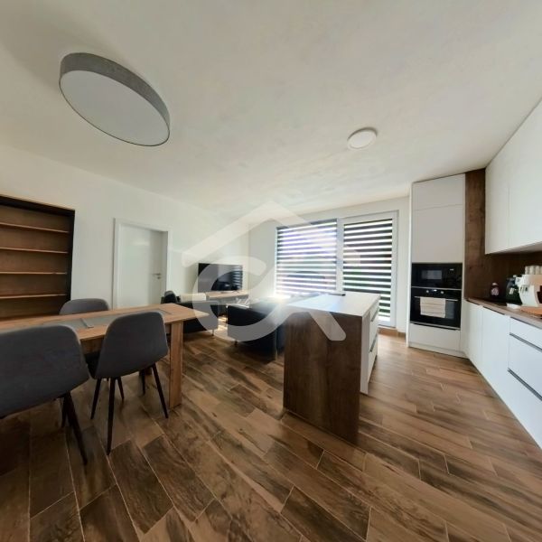 A kitchen in a 3-room apartment with a wooden decor floor and a dining table.