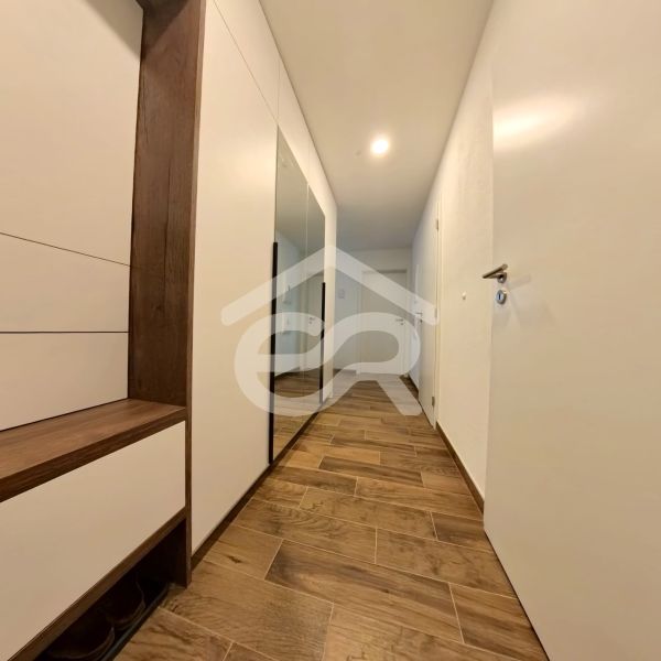 A hallway in a 3-room apartment with a wooden decor floor and white furniture.