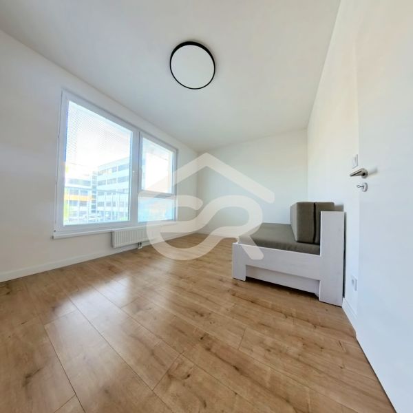A room in a 3-room apartment with a sofa and a wooden decor floor.