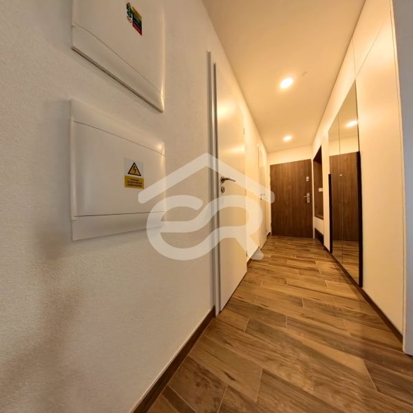 A hallway with a wooden decor floor and built-in wardrobes in a 3-room apartment.