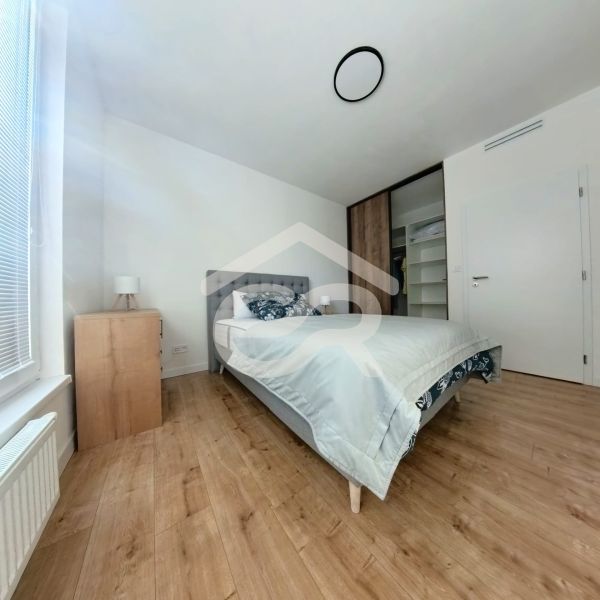 A bedroom with a wood-patterned floor and a built-in wardrobe in a three-room apartment.