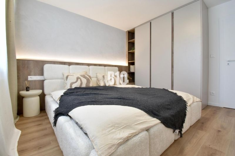 Bedroom in a 4-room apartment with a bed, built-in wardrobe, and wooden decor flooring.
