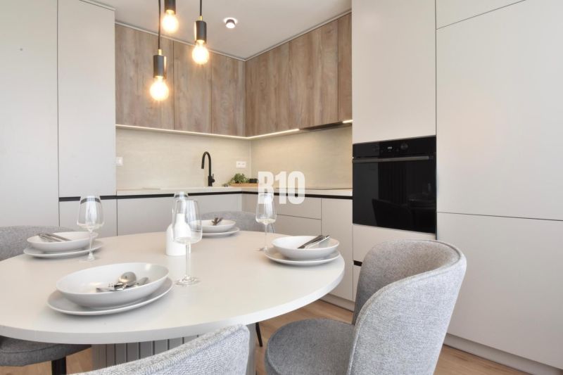Dining room in a 4-room apartment with a round table and a floor with a wooden decor.
