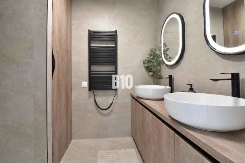 A bathroom in a 4-room apartment with oval mirrors and furniture with a wooden decor.