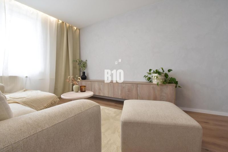 A bright living room in a 4-room apartment with wood-decor flooring and minimalist furniture.