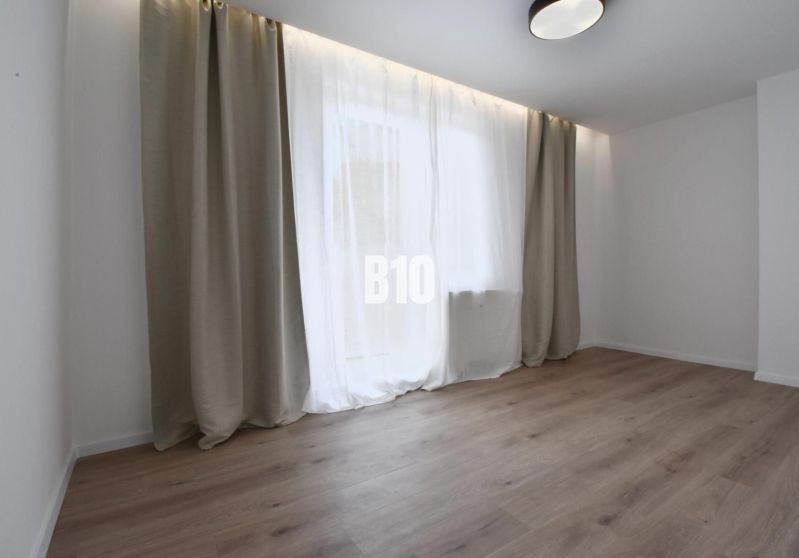A bright room with a wood-patterned floor and a large window in a 4-room apartment.