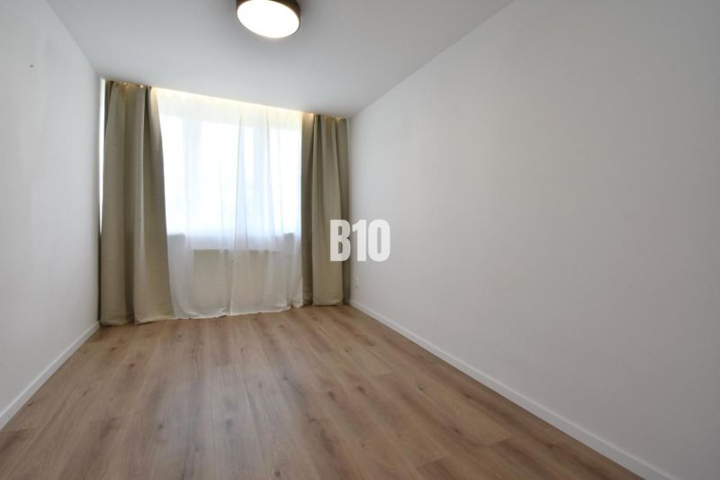 A room with curtains and a wooden decor floor in a 4-room apartment.