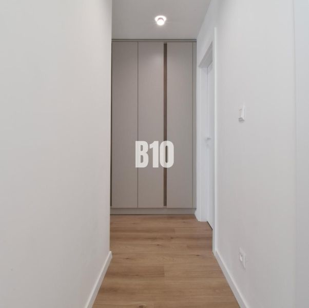 A hallway with a built-in wardrobe and a floor with a wood decor in a 4-room apartment.