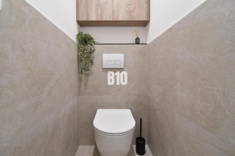 Bathroom with a wall-hung toilet, wood-effect flooring, and storage space.