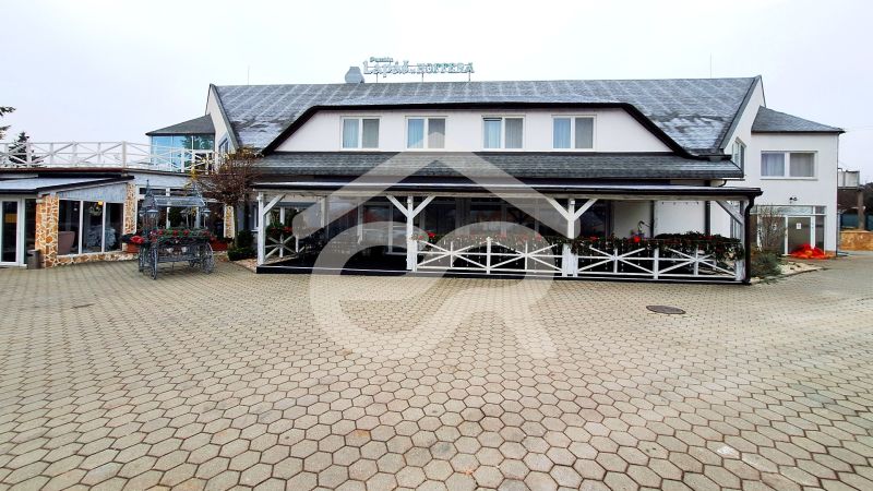 Exteriors of hotels and guesthouses in Veľký Lapáš with terraces and decorative flowers.