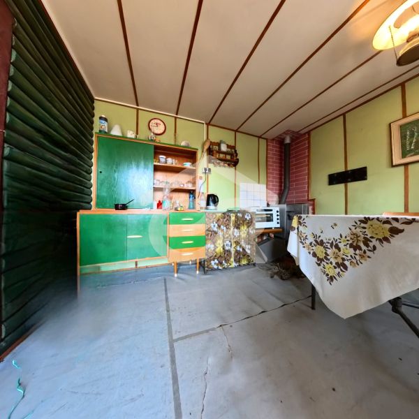 Interior of a cabin with older furniture, a hotplate on the counter, and floral textile decor.