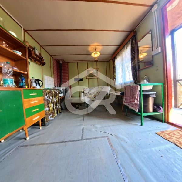 The interior of the cabin with simple furniture, a kitchenette, and a sink.