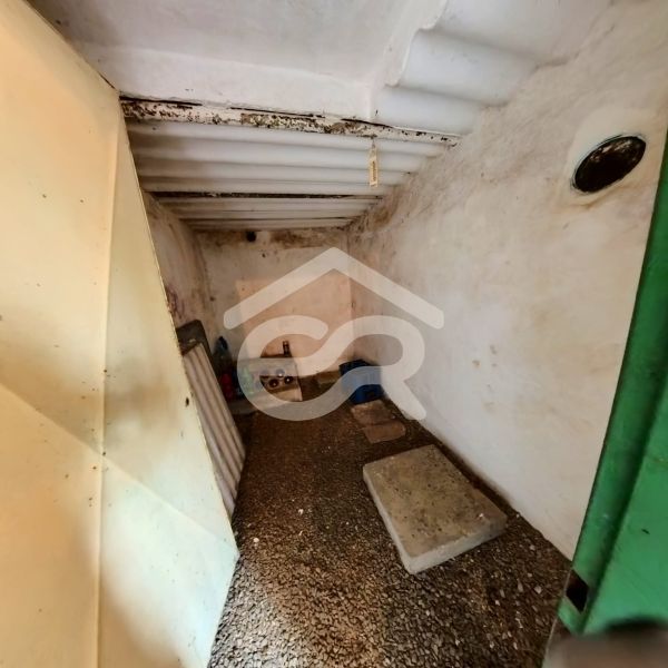 A narrow basement space in a cottage with a stone floor and white walls.