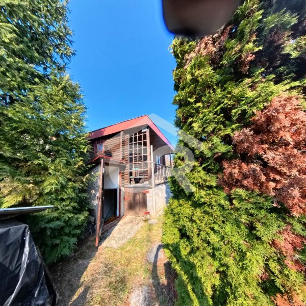 A cottage in Štitáre on Pri Kaplnke street surrounded by trees and a blue sky.