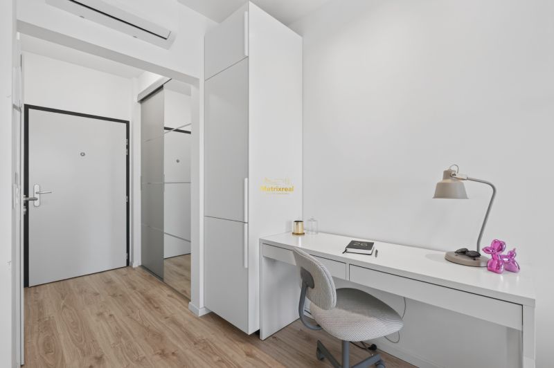A simple white workspace with a desk, chair, and floor with a wood decor.