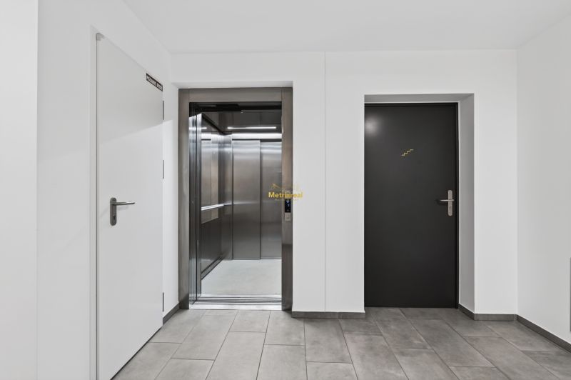 Studio apartment entrance hall with a lift and staircase, bright surroundings and neutral colors.