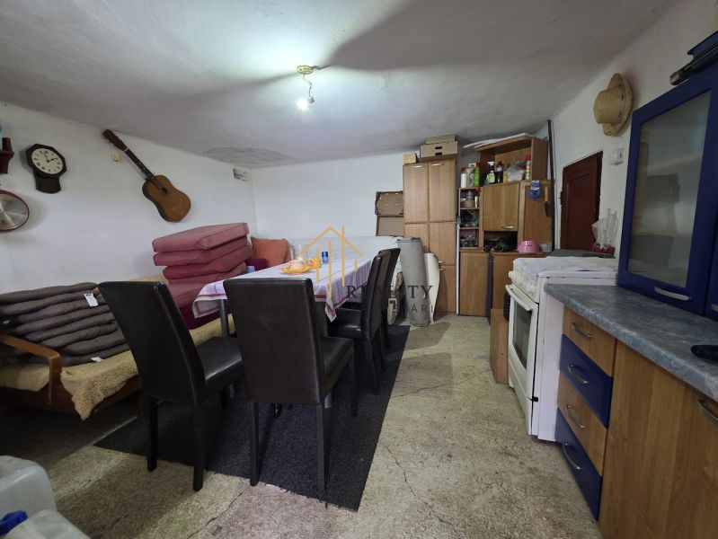 The interior of a cottage with a kitchen area, table, and chairs, a simple and cozy space.