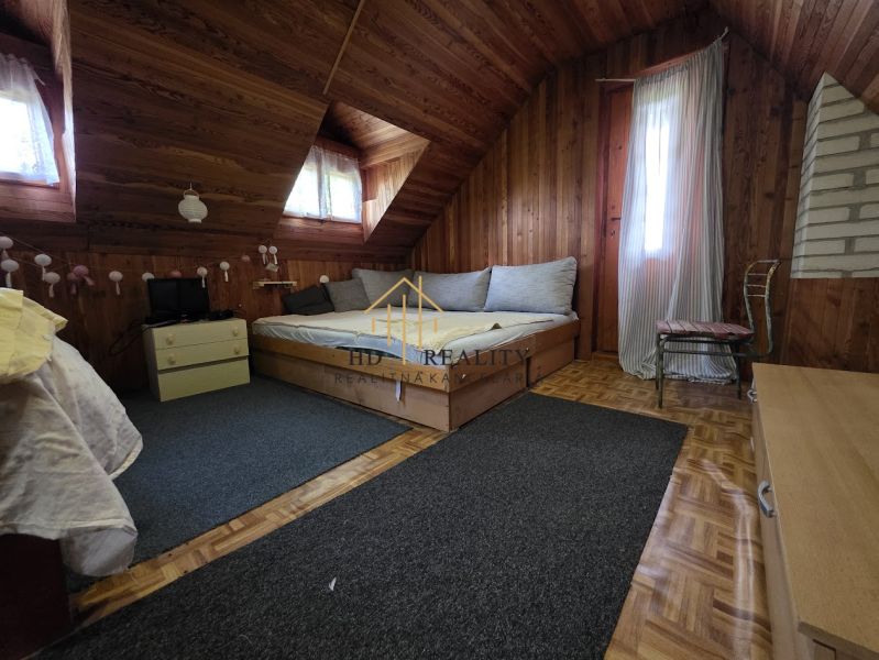 Attic room with a wooden ceiling, bed, and floor with a wooden decor.