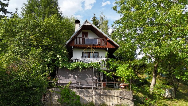 A cottage in Banská Bystrica surrounded by greenery with wooden elements and a balcony.