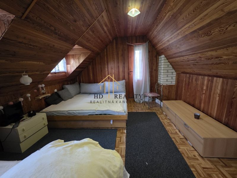 An attic room with wooden paneling and a wood-patterned floor in a cabin.