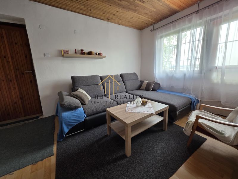 Living room in a cabin with a sofa, coffee table, and wooden decor flooring.