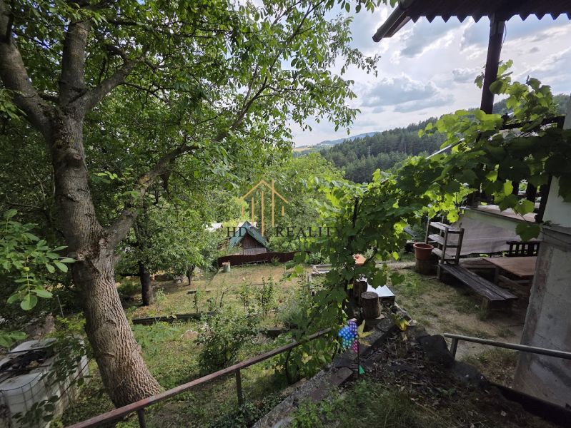 A cottage in a picturesque setting near Banská Bystrica, surrounded by lush greenery and trees.
