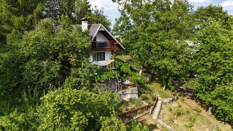 A cottage in Banská Bystrica surrounded by dense forest and green vegetation.