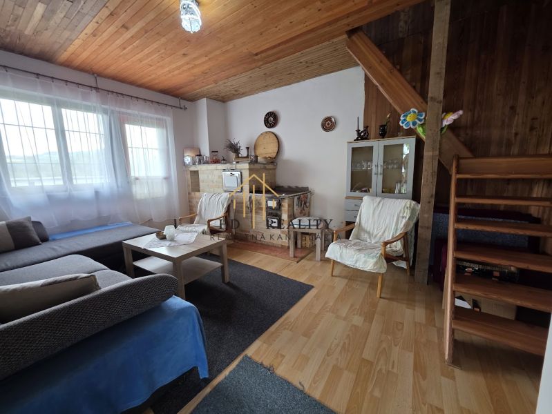 Interior of a cabin with a fireplace, sofa, and wooden decor flooring, cozy atmosphere.
