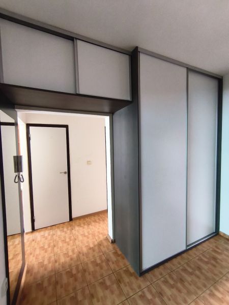 A hallway in a 3-room apartment with sliding wardrobes and a floor with a wooden decor.