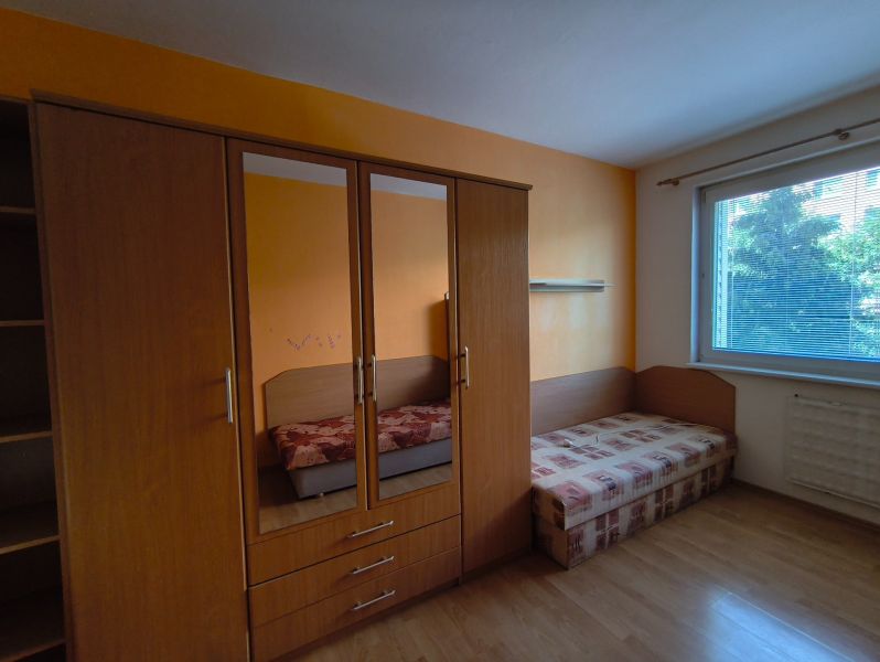 A room with a wooden floor decor, a wardrobe, and a bed in a 3-room apartment.