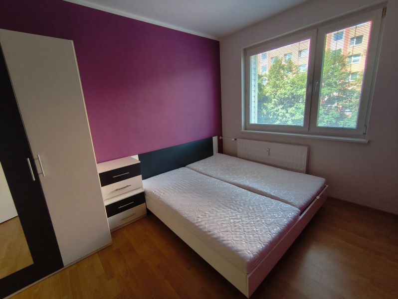 Bedroom in a 3-room apartment with two beds, a wardrobe, and a floor with a wooden decor.