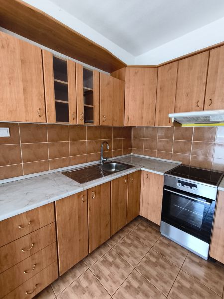 A kitchen with wooden cabinets in a 3-room apartment, flooring with a wooden decor.